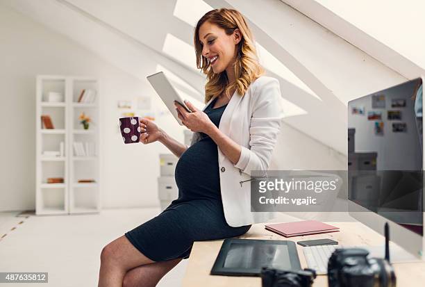 pregnant business woman using digital tablet in her office. - pregnant coffee 個照片及圖片檔