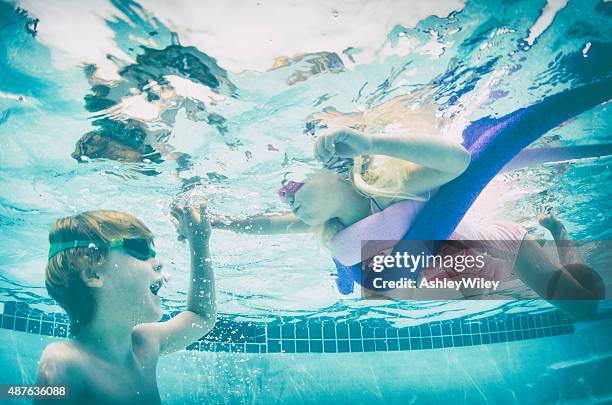 bruder und schwester schwimmen unter wasser, hände halten, helfen - babyschwimmen stock-fotos und bilder