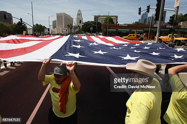 People carry a huge American flag in a march to the Metropolitan Detention Center during one a several May Day immigration-themed events on May 1,...