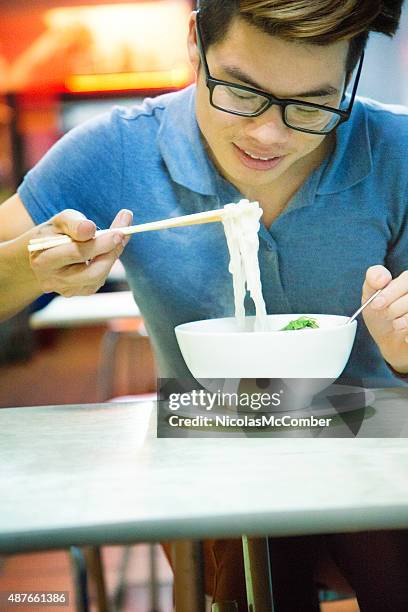 young vietnamese man eating pho soup with chopsticks - vermicelli stock pictures, royalty-free photos & images