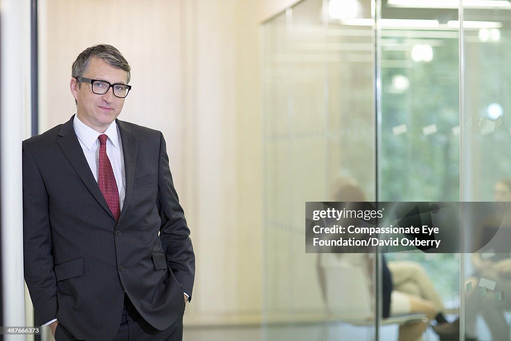 Businessman standing in modern office hallway