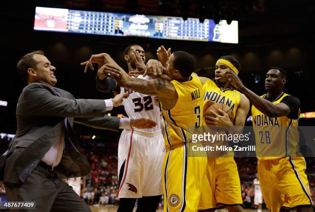 Forward Mike Scott of the Atlanta Hawks pushes forward George Hill of the Indiana Pacers in the face while Indiana Pacers head coach Frank Vogel,...