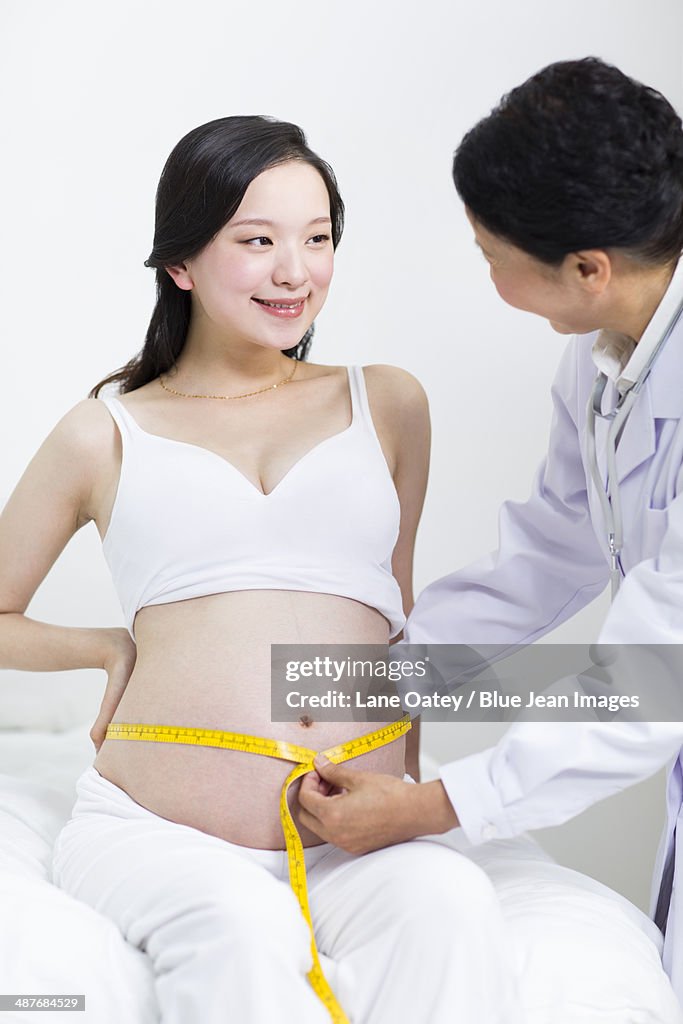 Doctor measuring pregnant woman's abdomen