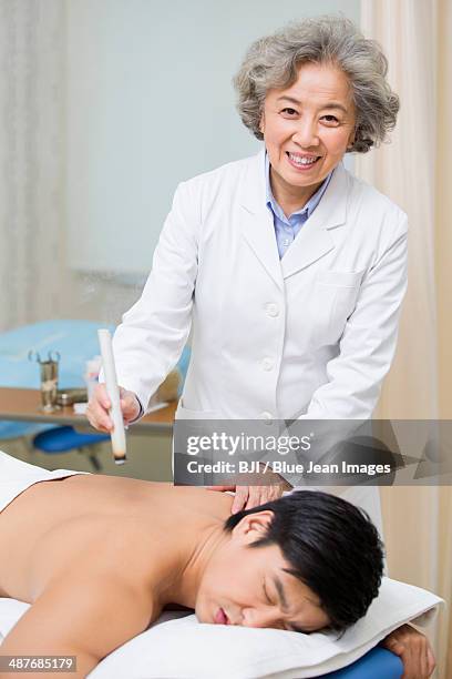 senior doctor giving moxibustion - acupuncture elderly stock pictures, royalty-free photos & images