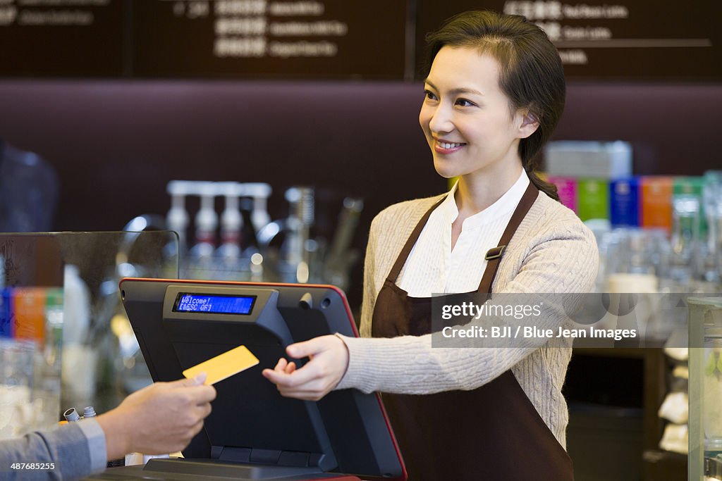 Customer paying by credit card in coffee shop