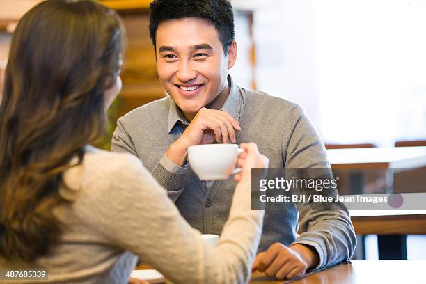 young couple chatting in cafe - asian man sitting at desk stock pictures, royalty-free photos & images