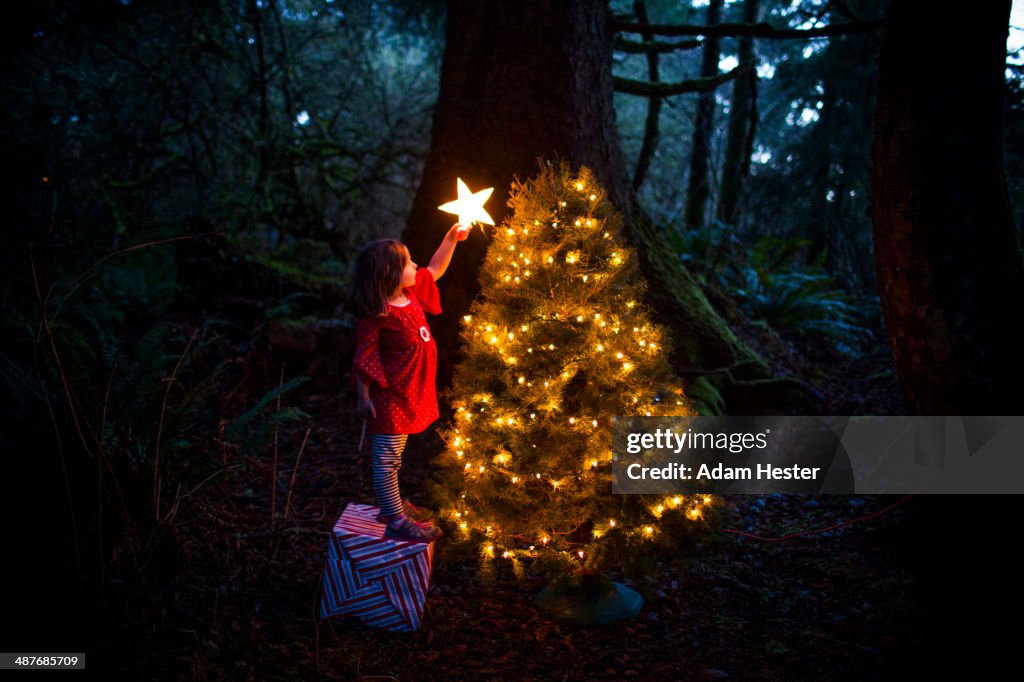 Caucasian girl decorating Christmas tree in forest