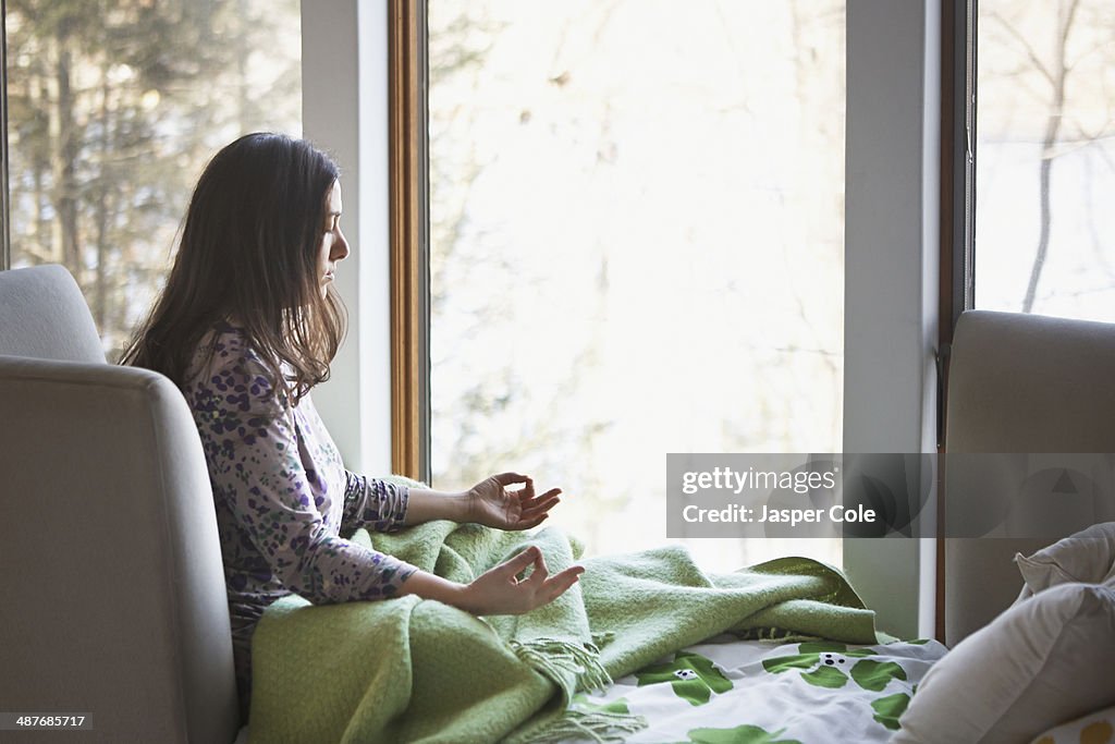 Caucasian woman meditating on sofa