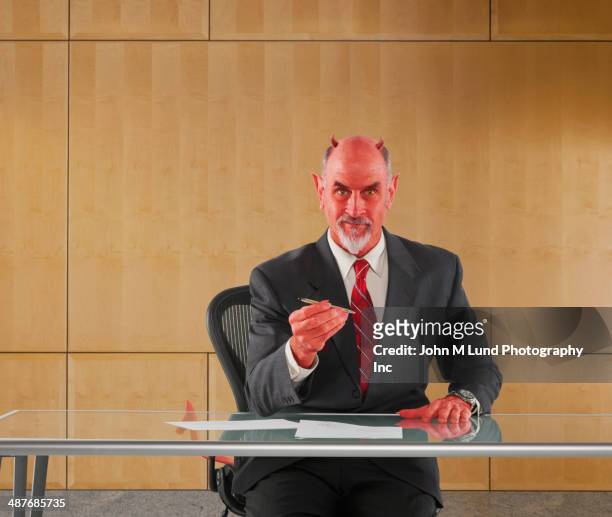 caucasian businessman in devil costume offering pen to sign contract - devil stock pictures, royalty-free photos & images
