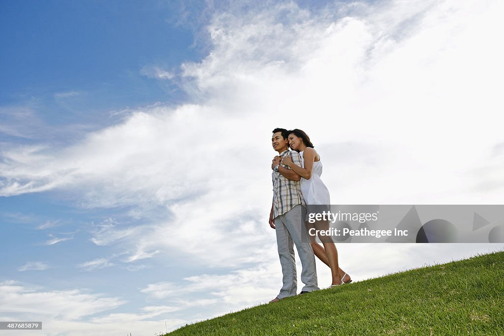 Couple hugging on grassy hillside