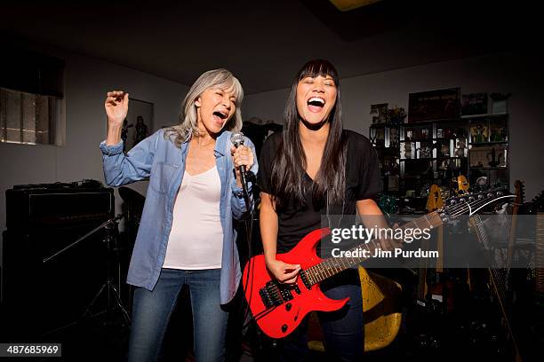 mother and daughter playing music guitar in basement - electric guitar stock-fotos und bilder