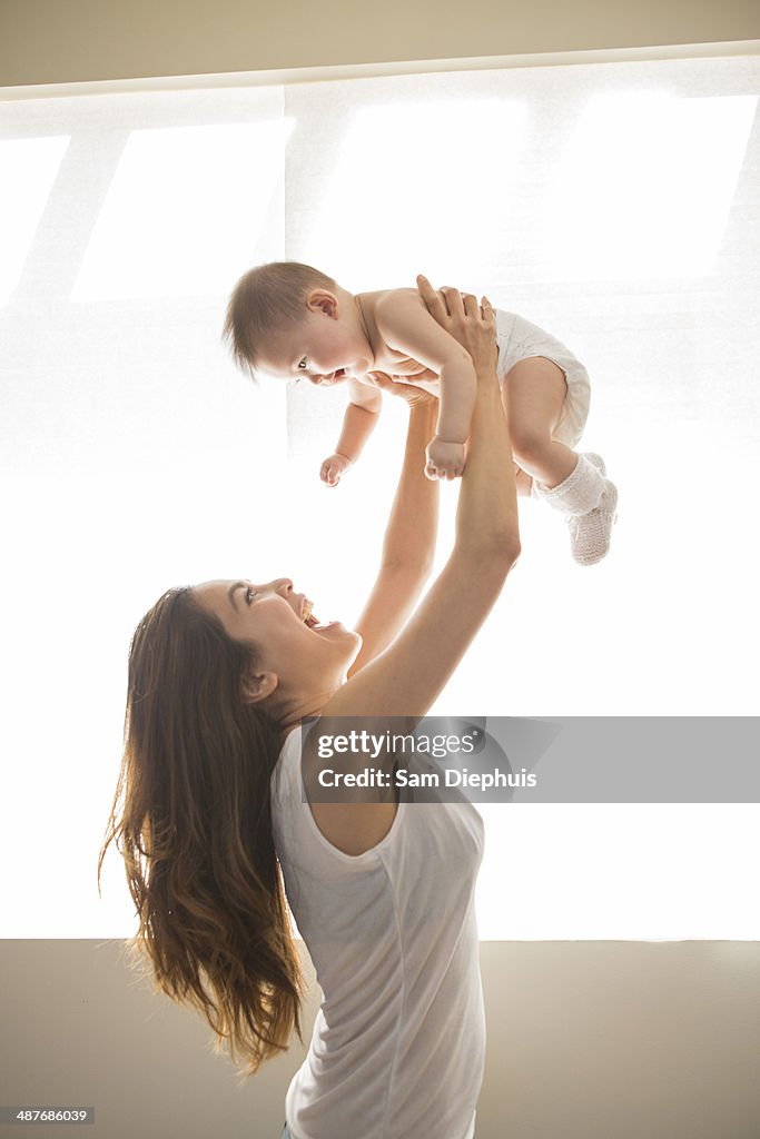 Mother lifting baby girl overhead