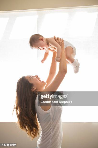 mother lifting baby girl overhead - mom picking up baby stock pictures, royalty-free photos & images