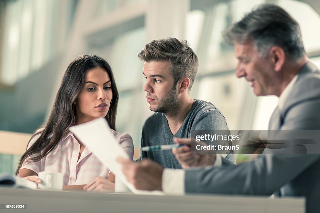 Suspicious couple having a business meeting with real estate agent.