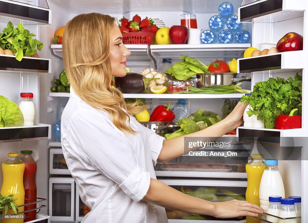 Happy female search something in the fridge