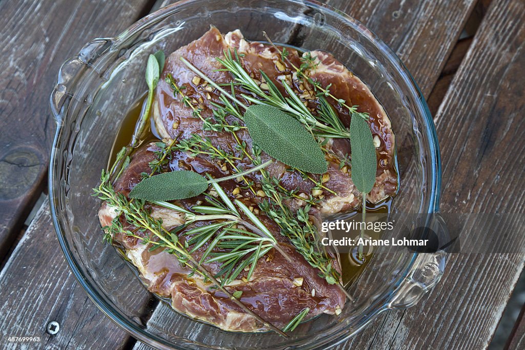 Pork neck steaks in marinade with herbs