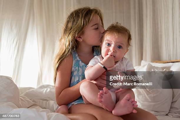 caucasian girl kissing sibling on sofa - kiss sisters foto e immagini stock