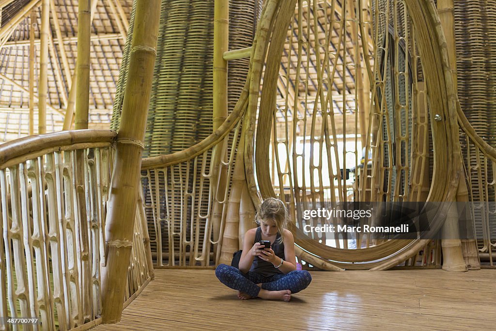 Caucasian girl using cell phone in bamboo house
