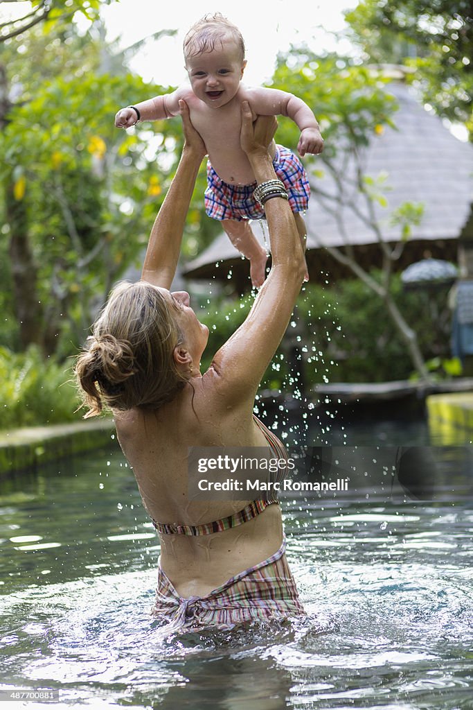 Caucasian mother and baby playing in pool