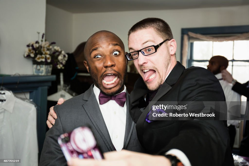 Groom and groomsman taking silly self-portrait