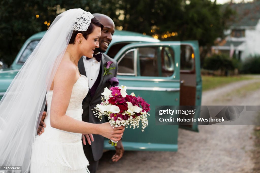 Newlywed couple outside vintage car