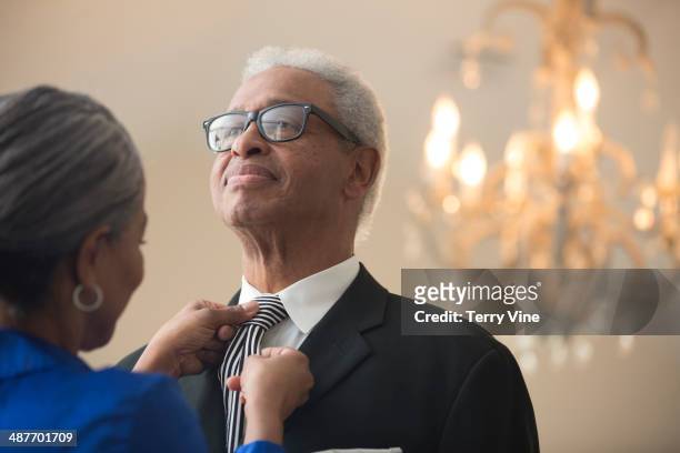 senior african american woman tying husband's tie - morgens anziehen stock-fotos und bilder