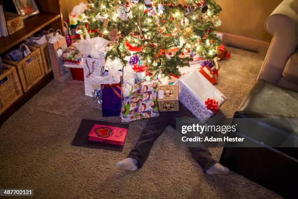 caucasian boy buried in christmas gifts - sapin de noel humour photos et images de collection