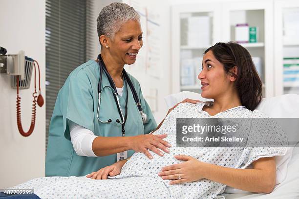 black doctor examining pregnant patient's belly - prenatal care stock pictures, royalty-free photos & images