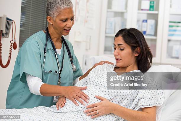 black doctor examining pregnant patient's belly - labour childbirth stock pictures, royalty-free photos & images