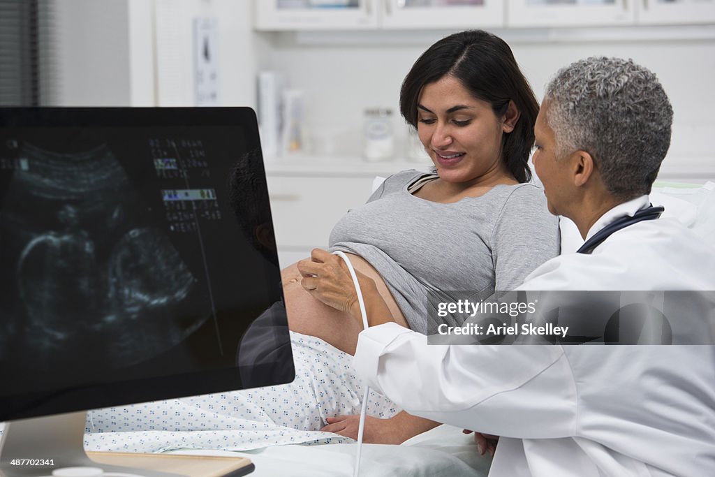 Black doctor giving pregnant patient ultrasound