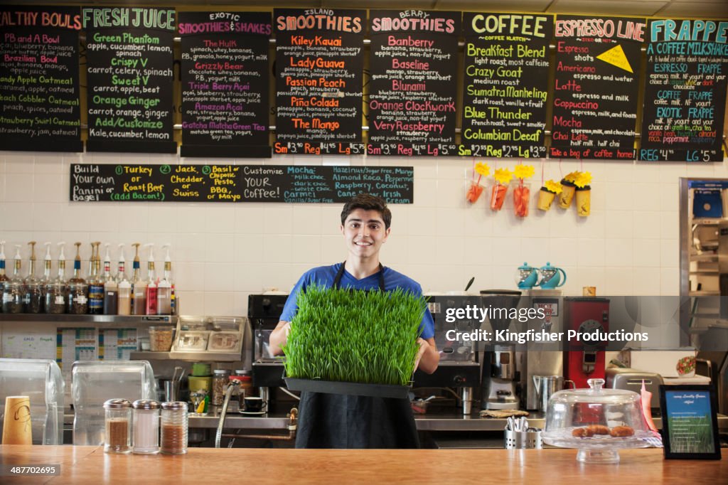 Hispanic teenage boy holding fresh wheatgrass in cafe