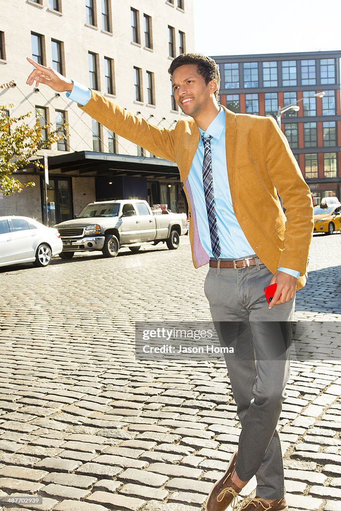 Mixed race businessman hailing taxi on city street
