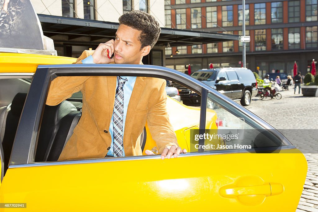 Mixed race businessman climbing out of taxi