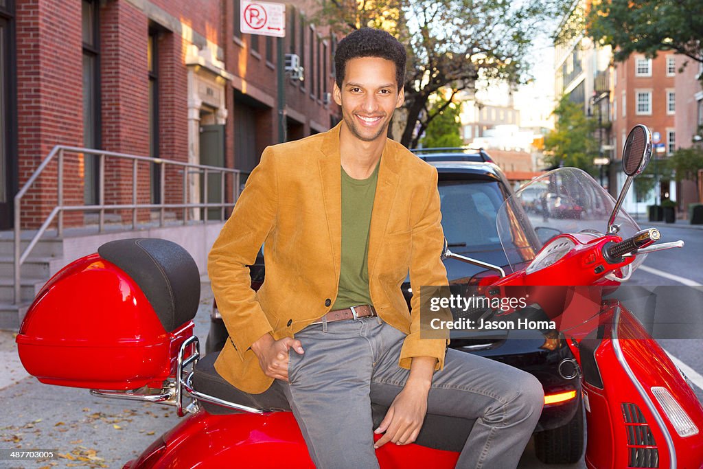 Mixed race man sitting on scooter on city street
