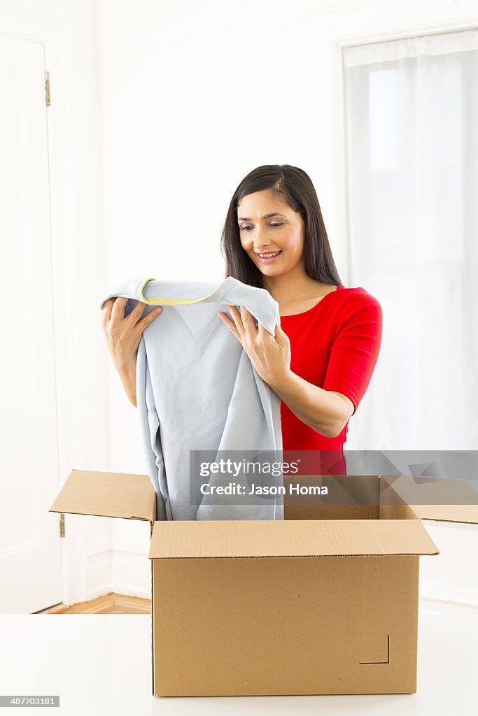 Mixed race woman unpacking cardboard box