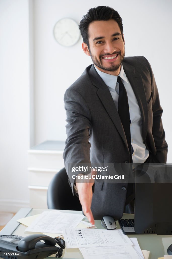 Mixed race businessman offering handshake in office