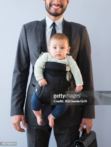 businessman carrying baby in carrier - baby carrier stock pictures, royalty-free photos & images