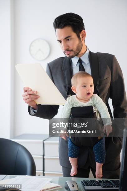 businessman working with baby in office - babytrage stock-fotos und bilder