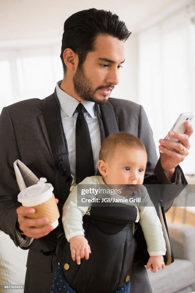 Businessman carrying baby and cell phone