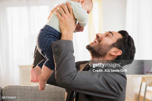 father playing with baby on sofa - un giorno nella vita foto e immagini stock