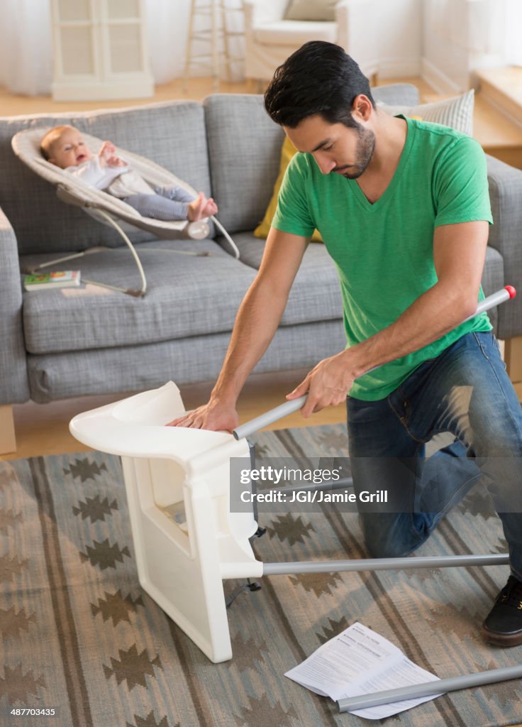 Father setting up highchair in living room