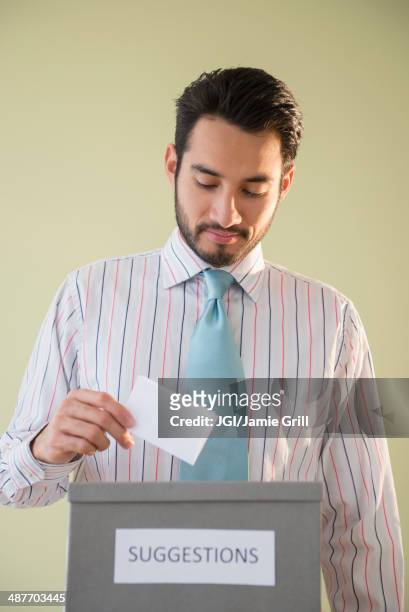 mixed race businessman placing idea in suggestion box - guy looking down stock pictures, royalty-free photos & images