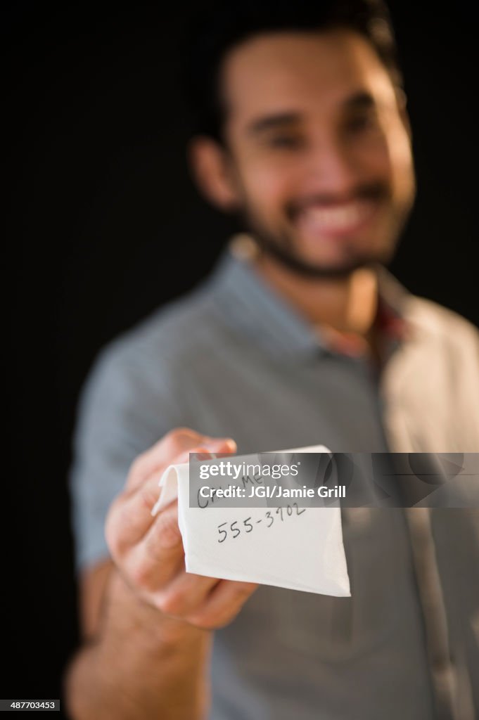 Mixed race man giving out phone number on napkin