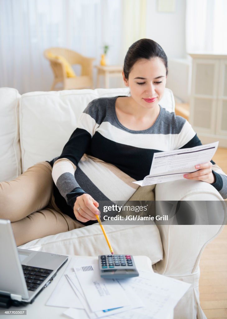 Pregnant Caucasian woman paying bills