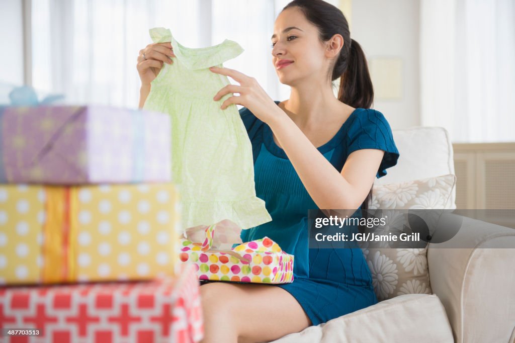 Pregnant Caucasian woman opening baby shower gifts