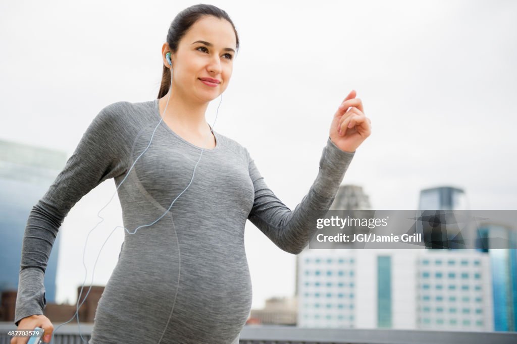 Pregnant Caucasian woman jogging on city street