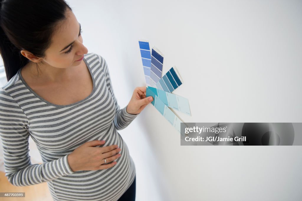 Pregnant Caucasian woman examining paint swatches