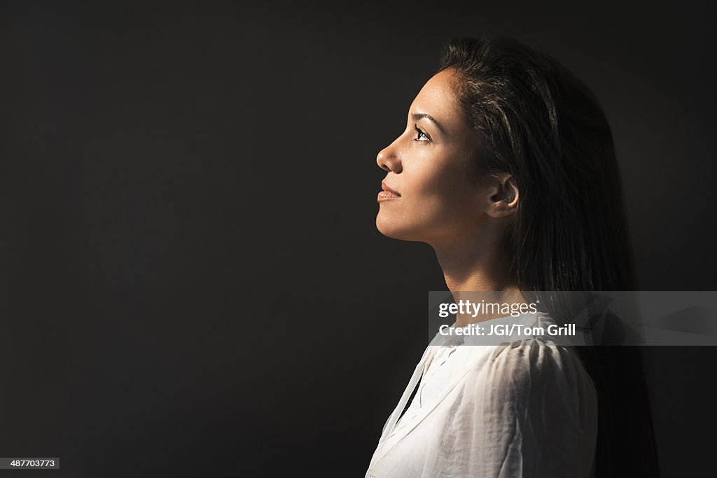 Hispanic woman looking up into light