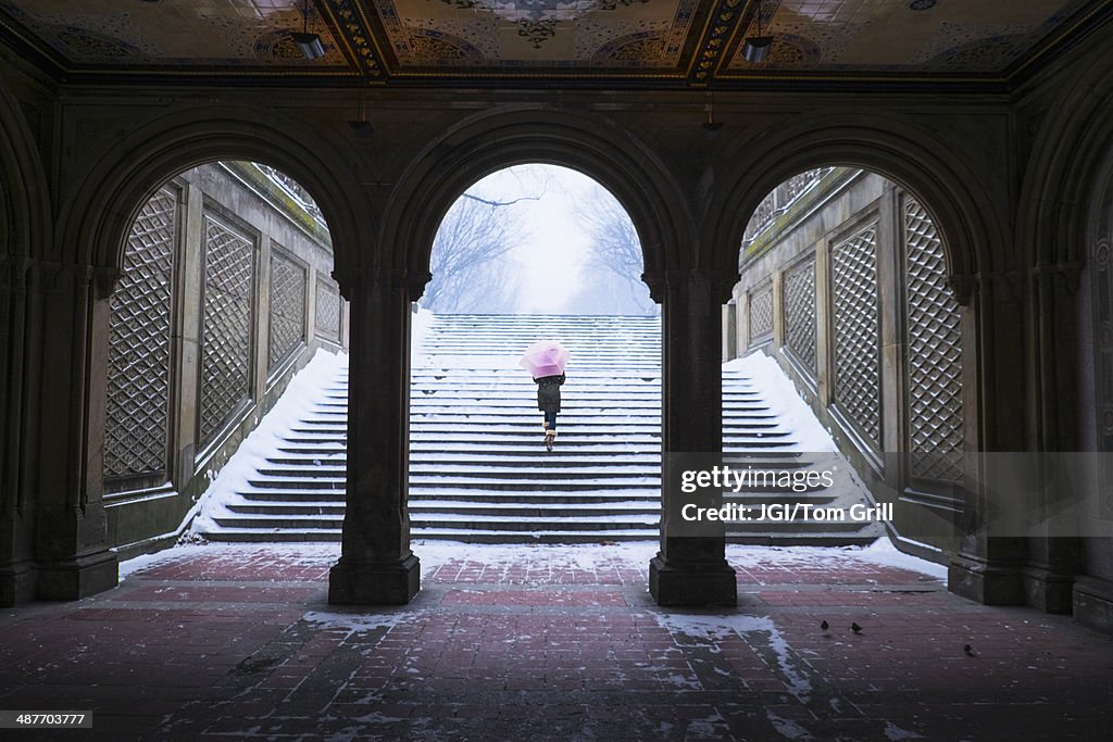 Asian woman walking up steps into snow