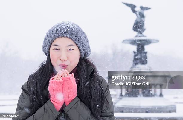 asian woman blowing on hands in snow - fingerless gloves stock pictures, royalty-free photos & images